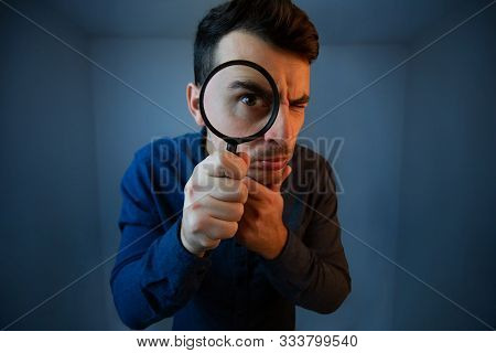 Surprised Young Man Student Holding Magnifying Glass Looking To Camera With A Pensive Emotion Isolat
