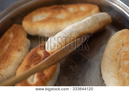 In A Pan With Vegetable Oil, Pies With Filling Are Fried Which Are Turned Over With A Wooden Spatula