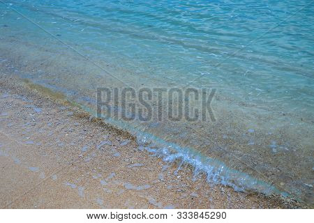 Clear Turquoise Water Rolls Onto The Sandy Shore