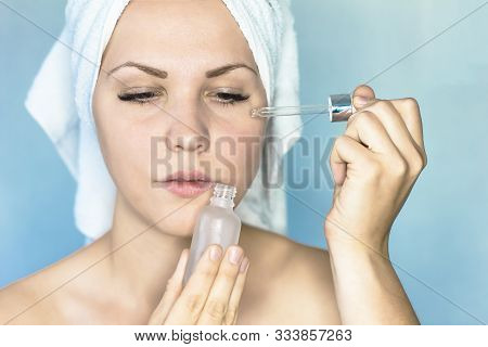 Portrait Of A Beautiful Woman, With One Hand Pipetting Serum On Her Face, With The Other Holding A G