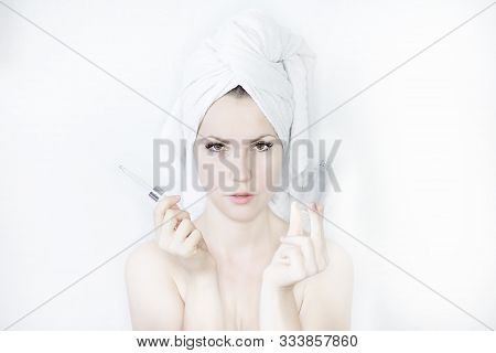 Well-groomed, Young Woman With A Towel On Her Head, After The Spa Procedure Uses Facial Skin Care Pr