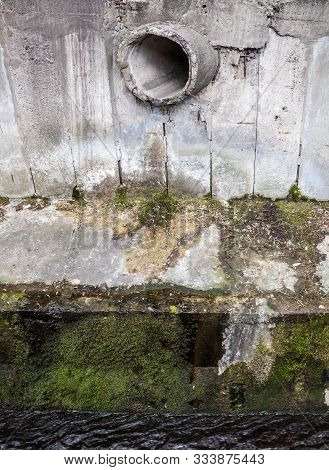 Concrete Run-off Pipe In The Concrete Wall Near The River. Round Orifice.