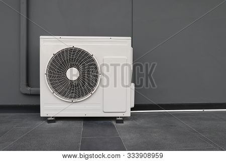 Condensing Unit Of Air Conditioning Systems. Condensing Unit Installed On The Gray Wall.