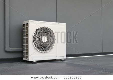 Condensing Unit Of Air Conditioning Systems. Condensing Unit Installed On The Gray Wall.