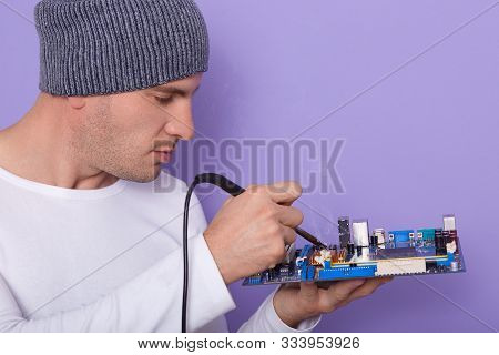 Technician Repair Faulty Spare Part Of In Electronic Technology Service. Side View Of Young Handsome