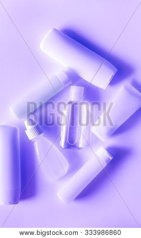 Cosmetic Mini Plastic Bottles Monochrome Neon Purple Background. Ecological Concept.
