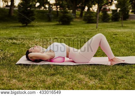 Young Fit Woman In Pink Sportswear Lies With Back On Pilates Ball To Stretch And Relax Back Muscles 