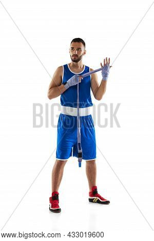 Full-length Vertical Portrait Of Professional Boxer Tying Boxing Handwraps Isolated Over White Backg