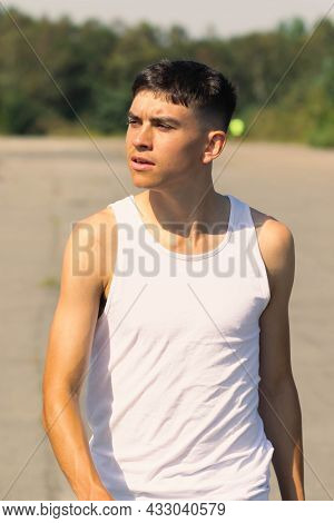 An 18 Year Old Teen Boy In A Sleeveless Top On A Late Summer's Day