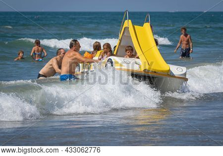 Family On A Marine Pedal Catamaran Trying To Land Across The Waves At Marina San Nicola Beach In Ita