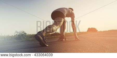 A Young Man Prepares For A Quick Jog On An Asphalt Road, Around The Field. A Runner Warms Up, Stretc