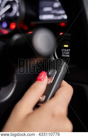 The Car Owner Holds In His Hand A Remote Control Device For Keyless Entry Near The Start Stop Button
