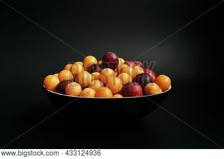 Ripe Cherry Plums Of Different Varieties In A Black Bowl On The Table.