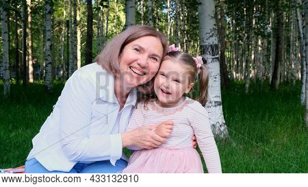 Happy Laughing Tender Grandmother Playing And Hugs Up Her Little 3 Year Old Granddaughter. The Conce