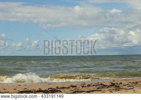 The Baltic Sea In August. Sand, Seaweed On The Shore, Waves, Beautiful Clouds And The Sun. High Qual