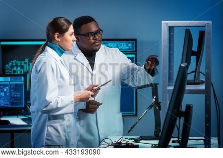 Group Of Microelectronic Engineers Discussing In A Modern Microprocessor Manufacture Lab. Workplace 
