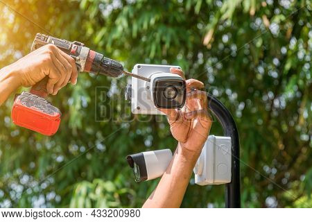 Technician Installing Cctv Camera  Security System At Car Park And And Installed White Plastic Boxes