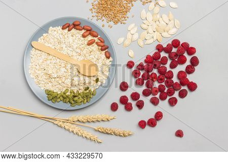 Pumpkin Seeds, Nuts And Oatmeal In Gray Bowl. Wheat Spikelets And Raspberries On Table. Flat Lay. Gr