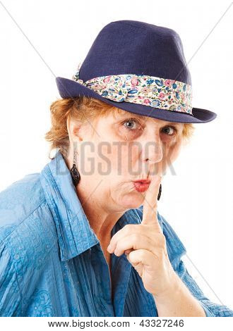 Mujer de mediana edad poniendo su dedo a los labios en un gesto hushing.  Aislado en blanco.