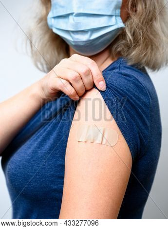Vaccinated Young Woman Showing Arm With Plaster, Female Person In Mask After Getting Covid-19 Vaccin