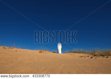 Man In Arabic Clothes Walking Through Desert On Sunny Day, Back View