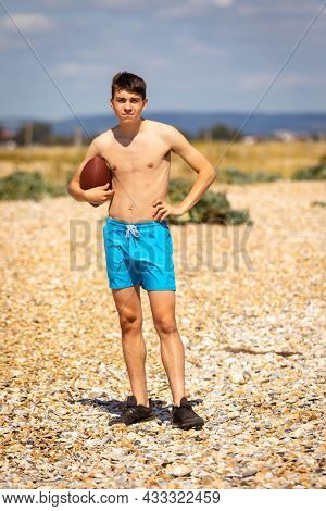 A 18 Year Old Caucasian Shirtless Teenage Boy Playing On A Beach With An American Football