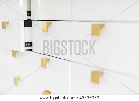 White sleek drawers with golden handles.