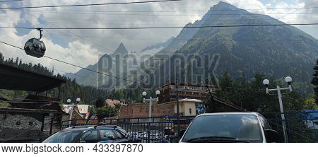 Dombay, Russia, August 28, 2021: Cabins Of The Ski Lift Against The High Snow-capped Caucasus Mounta