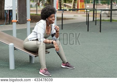 Young restful sportswoman communicating outdoors while enjoying break after workout