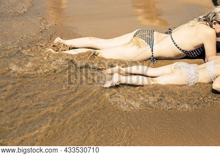 Mother And Daughter Rest Lying By The Sea