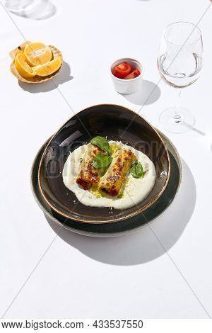 Italian beef cannelloni with bolognese ragu, bechamel sauce and cheese. Baked pasta cannelloni with meat and cheese parmesan. Italian aesthetic white table. Harsh shadow in Italian menu restaurant