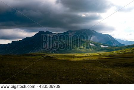 Beautiful photography of the mountain Oshten. Dramatic sky in the background and sun rays. Idea of tourism and hiking, breathtaking nature. High mountain in Russia.