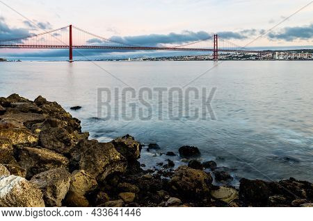 The 25 De Abril Suspension Bridge Over Tagus River In Lisbon, Portugal At Sunrise