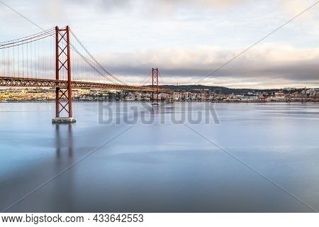 The 25 De Abril Suspension Bridge Over Tagus River In Lisbon, Portugal At Sunrise