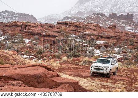 Moab , UT, USA - February 9, 2020:  Toyota 4runner SUV (2016 trail edition, stock vehicle) with recovery ladders on roof racks on a 4x4 trail in winter conditions with Fisher Towers in background.