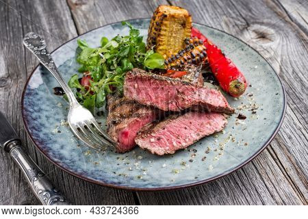 Traditional barbecue wagyu sirloin beef steak with salad and vegetable offered as close-up on a design plate