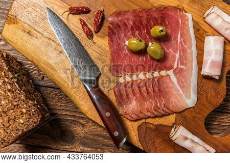 Meat, Ham With Herbs And Spices On Wooden Background. Schwarzwald Ham With Green Olives. Thinly Slic