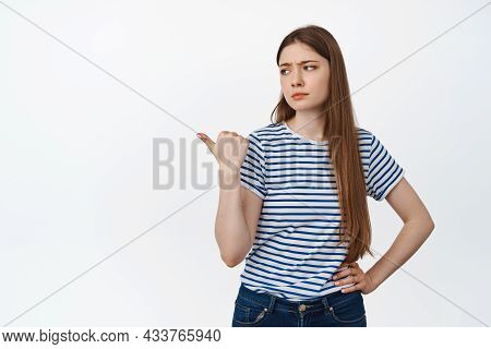 Image Of Skeptical Young Woman Frowning, Pointing And Looking Lef With Doubtful, Unimpressed Face Ex