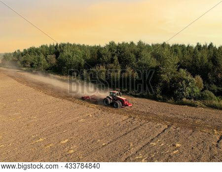 Agricultural Tractor On Cultivating Field For Sowing Seeds. Farming And Seeding Concept. Seed Sowing