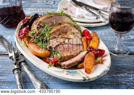Traditional French leg of lamb with vegetable and fruits served as close-up on a design plate