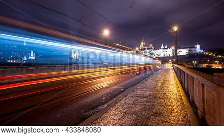 Night Tram In Prague. Motion Blurred Tram On Manes Bridge With Illuminated Prague Castle On Backgrou
