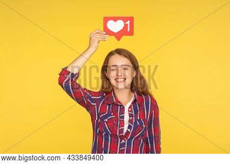 Portrait Of Joyful Girl With Closed Eyes Smiling And Holding Social Media Heart Like Icon Over Head,