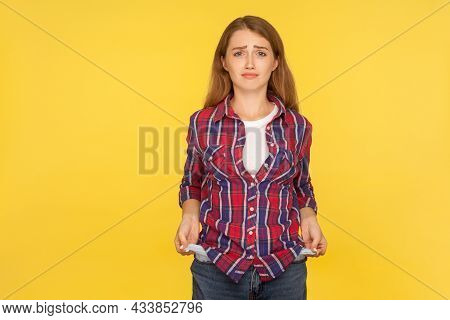 Portrait Of Upset Poor Ginger Girl In Shirt Showing Empty Pockets And Looking Frustrated About Loans