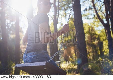 Woman in nature in sunset. People in nature.Woman relaxing on swing in nature in sunset. people. Happy people nature. Happy woman on swing in nature sunset in nature. Woman on swing in forest nature sunset. Woman. People. Sunset. Nature.