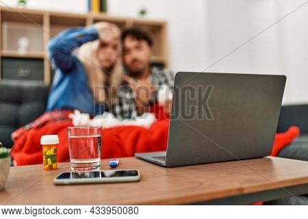 Young ill couple having medical teleconsultation using laptop at home.