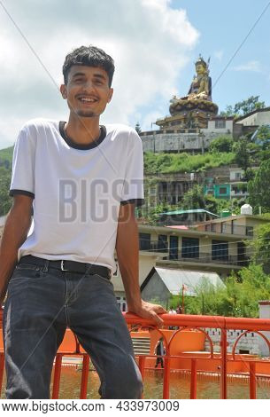 A Handsome Guy Smiling Sitting On Safety Barrier By Lake And Beautiful Hilly Area Of Tso-pema And St