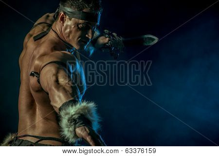 Portrait of a handsome muscular ancient warrior with a sword.