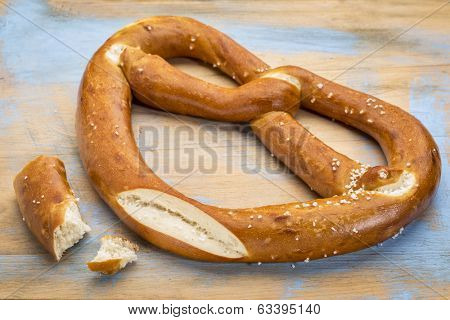 a big pretzel twist with salt on a painted wooden cutting board