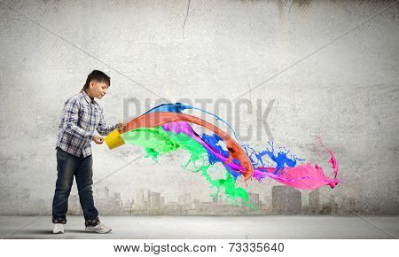 Young boy splashing colorful paint from bucket