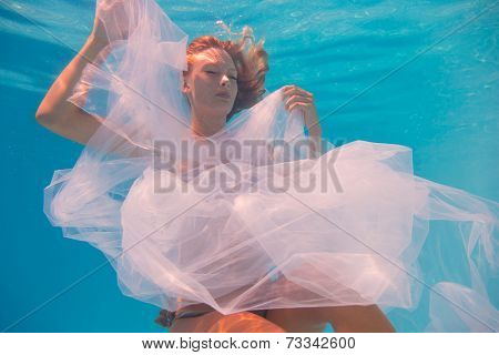 Young woman swimming undewater in the swimming pool